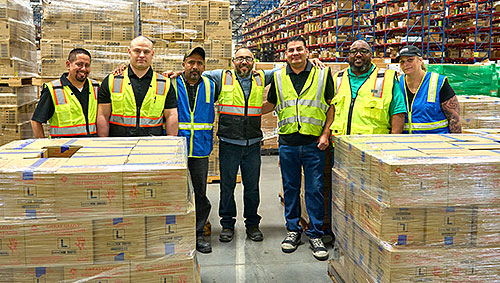 Seven Airgas distribution center associates standing shoulder to shoulder smiling.