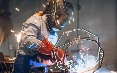 A woman welder, wearing proper PPE.