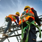 Construction workers climbing a scaffold wearing hard hats, safety vests and fall protection