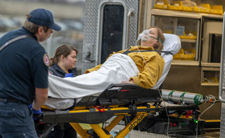EMT's loading a senior on a strecher into an ambulance