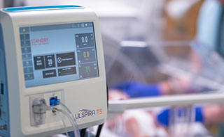 A hospital worker pushing a cart with two Ulspira cylinders