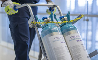 A hospital worker pushing a cart with two Ulspira cylinders