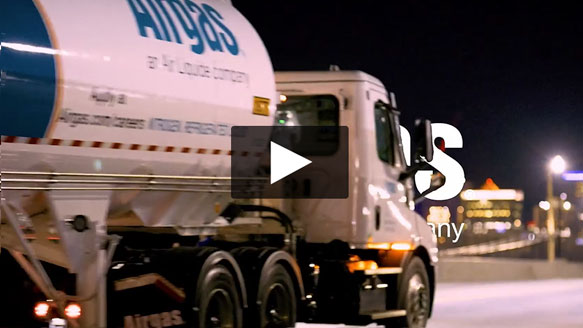 A closeup of an Airgas bulk delivery truck driving before sunrise