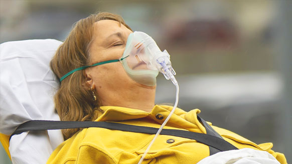 A woman on a gurney wearing an oxygen mask