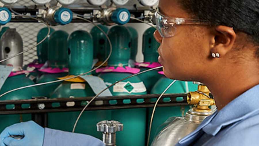 A woman testing gas purity wearing safety glasses and a lab coat.