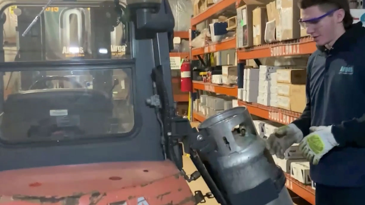 Warehouse worker checking the propane tank on a forklift