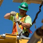 Worker wearing a hard hat and safety vest wrenching a large bolt