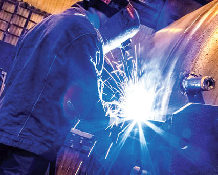 Welder, wearing a welding helmet & welding gloves, MIG/GMAW welding carbon steel  using ARCAL Force premium shielding gas.