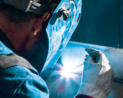 Welder, wearing welding helmet & welding gloves, TIG/GTAW welding with ARCAL Prime premium shielding gas.
