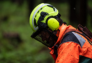 A worker with protective ear, face and head gear looks down at the job.