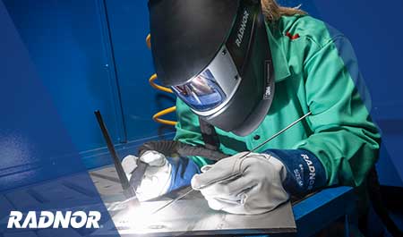 Welder using RADNOR welding tools and consumables, while wearing RADNOR welding helmet by 3M Speedglas, welding jacket and welding gloves.
