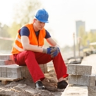 Worker taking a break on a hot summer day, wearing a hard hat and safety vest