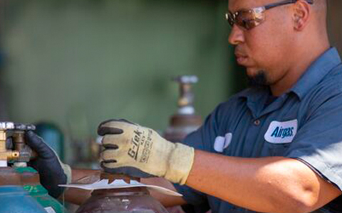 An Airgas technician safety handles a packaged gas cylinder.