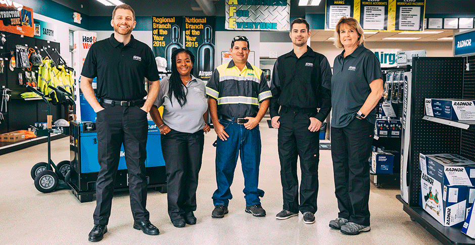 Five Airgas associates of different ages and genders standing together in an Airgas retail branch showroom.