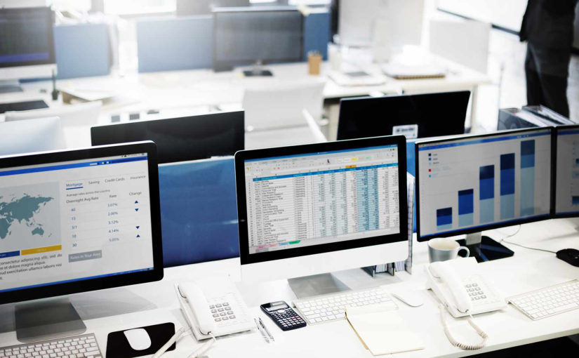 A row of desktop computers display organized data in various formats.