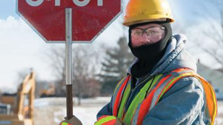 A flagger-force worker wearing the proper PPE to stay warm on a winter day